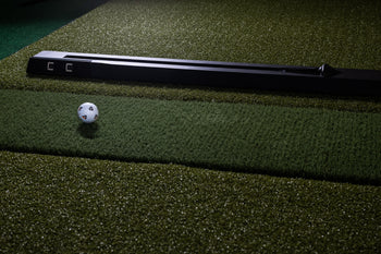 NOVA Golf Entertainment System by Open Launch sleek black launch monitor on green turf mat with
   golf ball